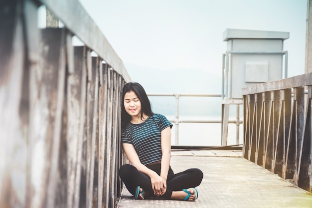 portrait of young woman sitting at walk way to water level gate and take a deep breath at countrysid