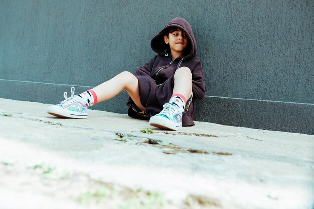 Photo portrait of a young woman sitting on wall