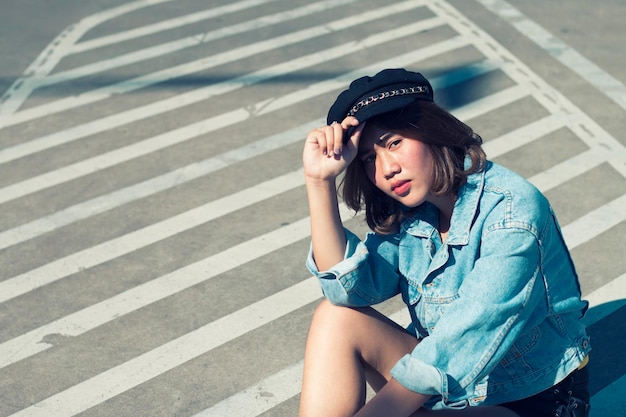 Portrait of young woman sitting on zebra crossing in city