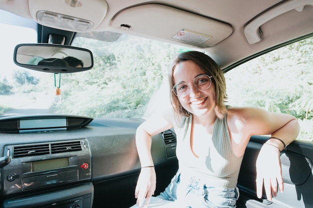 Portrait young woman smiling inside car on a road trip for\
directions. reading a map. cheerful loving couple relaxing on\
vacation. trip on route vacation. happy and smiling to camera.