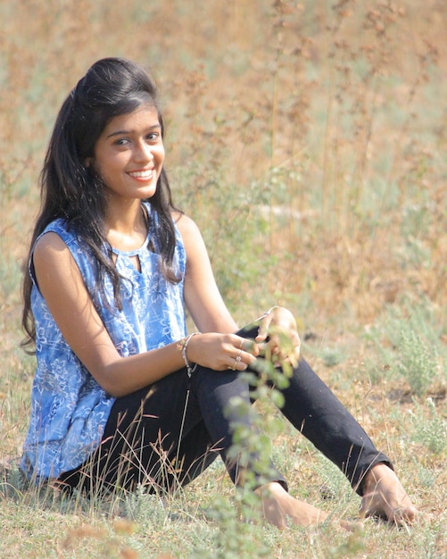 Foto ritratto di una giovane donna che sorride mentre è seduta su un campo erboso