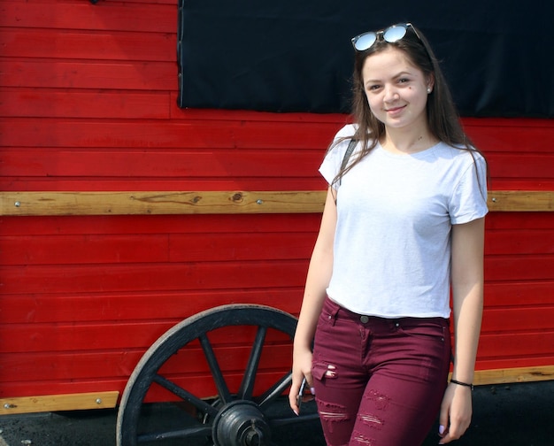 Photo portrait of young woman smiling while standing against red wall