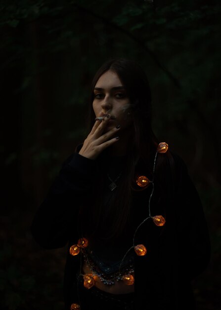 Photo portrait of young woman smoking in dark