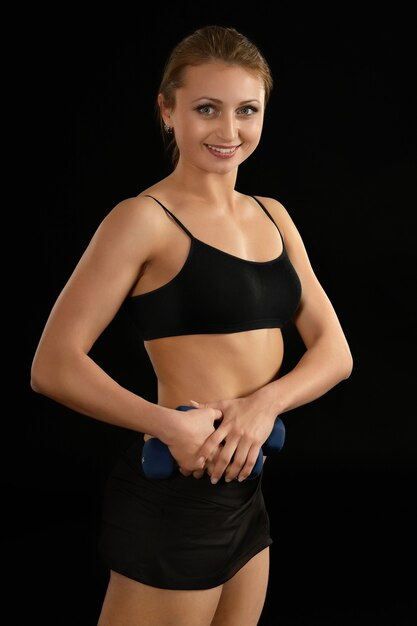 Portrait of young woman in sportswear on black background