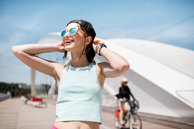 Portrait of a young woman in sportswear standing on the modern white bridge in Lyon city