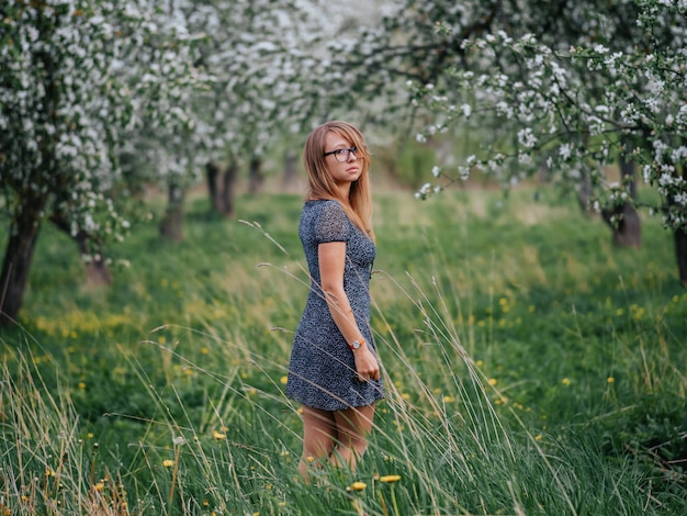 Portrait of a young woman in a spring green apple garden