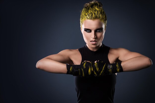 Portrait of young woman standing against black background