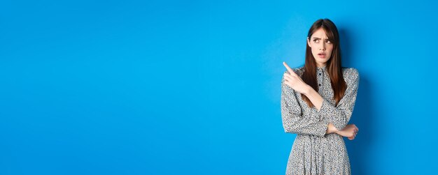 Portrait of young woman standing against blue background