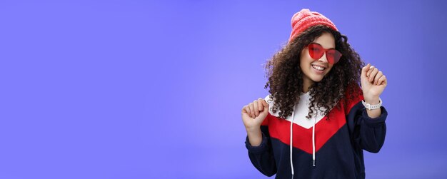 Portrait of young woman standing against blue background