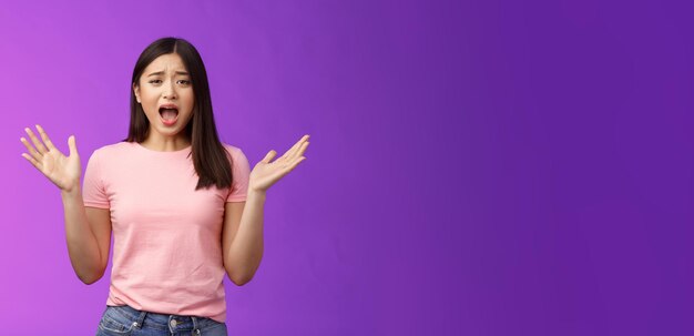 Portrait of young woman standing against blue background