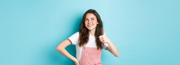 Portrait of young woman standing against blue background