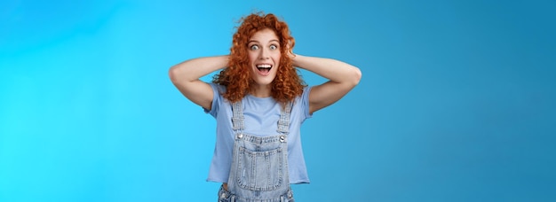 Portrait of young woman standing against blue background