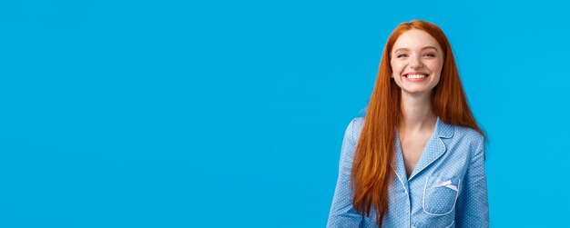 Portrait of young woman standing against blue background