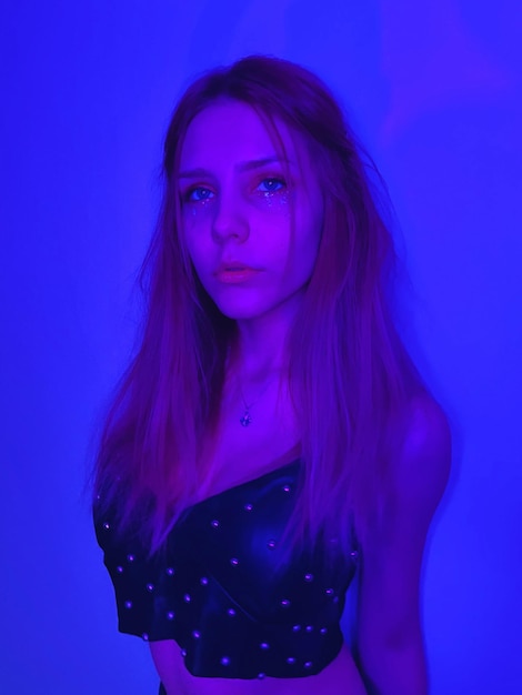 Portrait of young woman standing against blue background