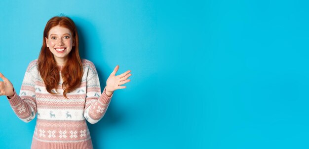 Portrait of young woman standing against blue background