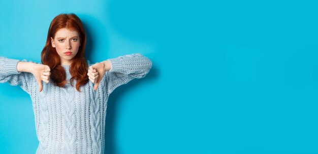 Portrait of young woman standing against blue background