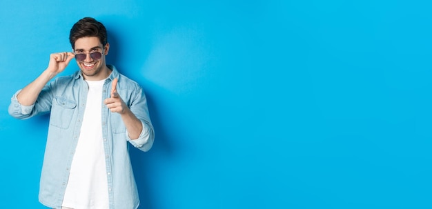 Portrait of young woman standing against blue background