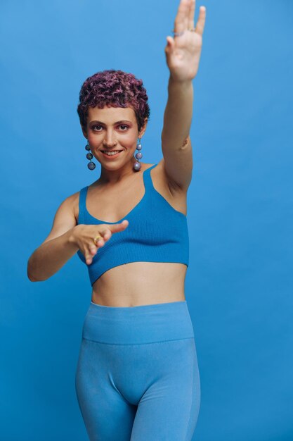 Portrait of young woman standing against blue background