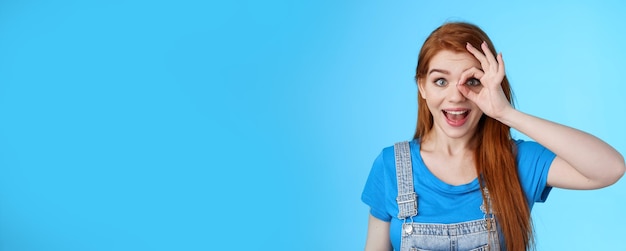 Portrait of young woman standing against blue background