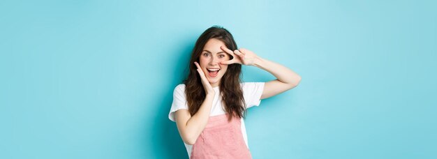 Portrait of young woman standing against blue background