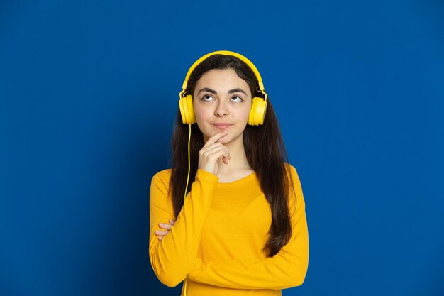 Portrait of young woman standing against blue background