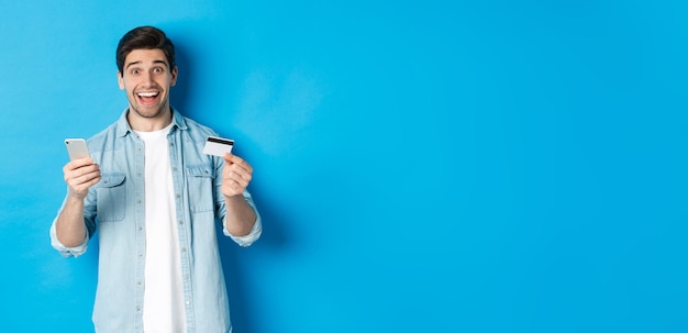 Portrait of young woman standing against blue background