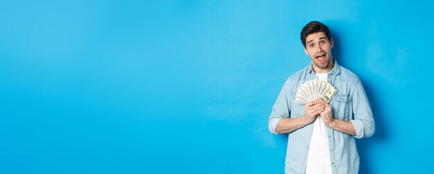 Portrait of young woman standing against blue background