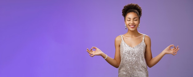 Portrait of young woman standing against blue background