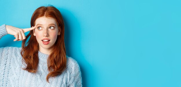 Portrait of young woman standing against blue background