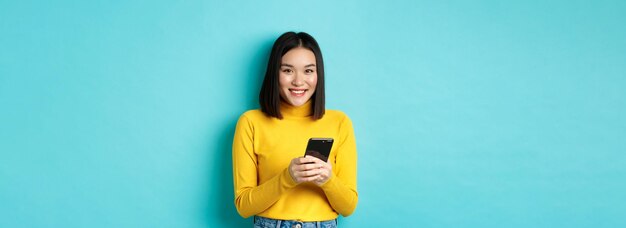 Portrait of young woman standing against blue background