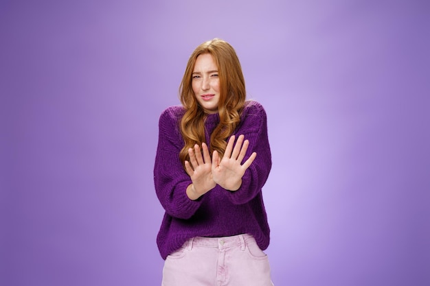 Portrait of young woman standing against blue background