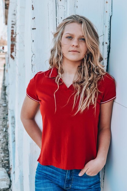 Portrait of young woman standing against brick wall