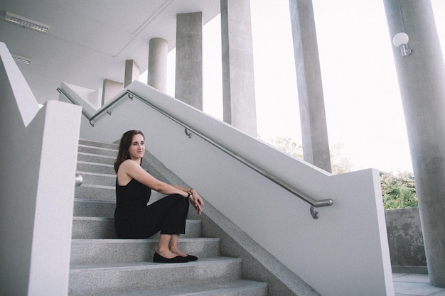 Portrait of young woman standing against building