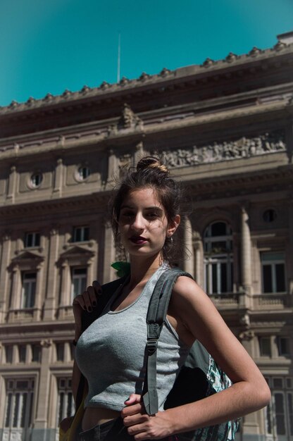 Portrait of young woman standing against building