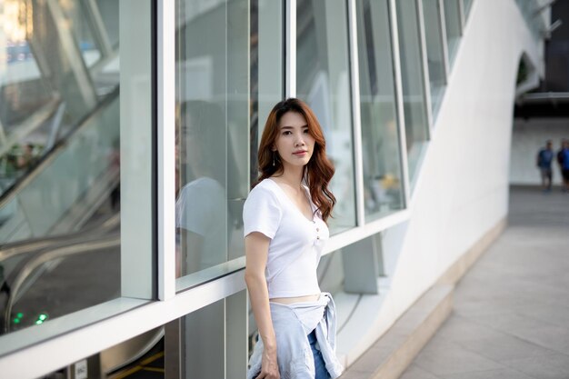 Portrait of young woman standing against building