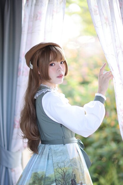 カーテンに背を向けて立っている若い女性の肖像画