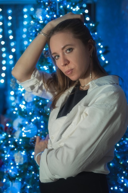 Portrait of young woman standing against illuminated christmas tree