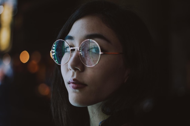 portrait of young woman standing against illuminated city at night