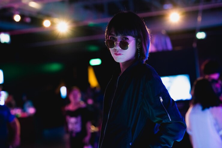 Photo 夜に照らされたライトに照らされて立っている若い女性の肖像画