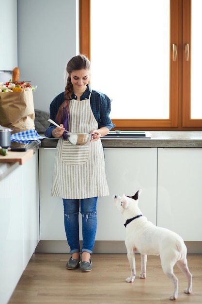 Portrait of young woman standing against kitchen background