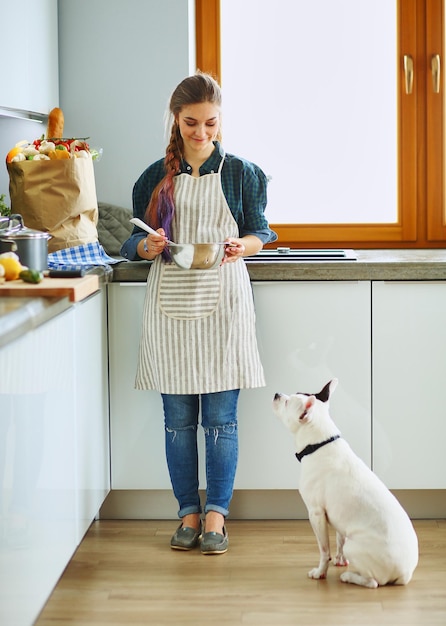 Portrait of young woman standing against kitchen background