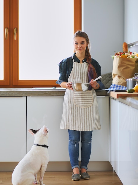 Портрет молодой женщины, стоящей на фоне кухни