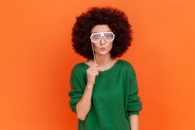 Portrait of young woman standing against orange background