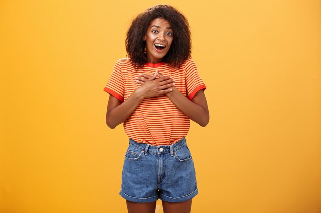 Portrait of young woman standing against orange background