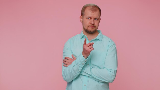 Portrait of young woman standing against pink background