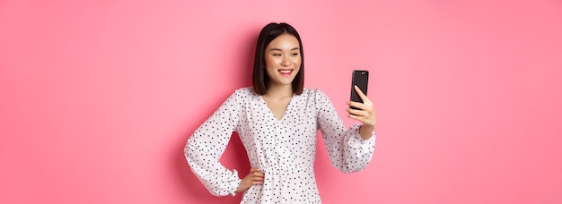 Photo portrait of young woman standing against pink background