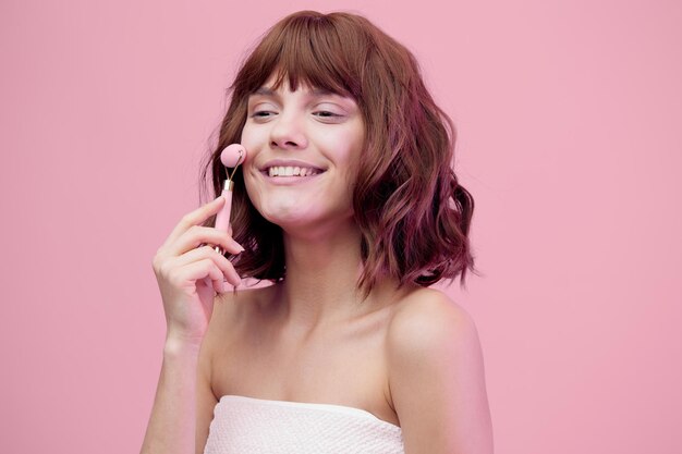 Portrait of young woman standing against pink background