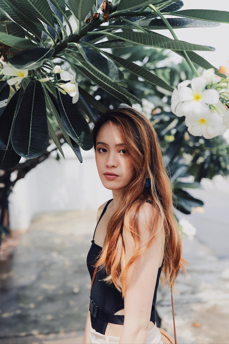 Photo 公園の植物に寄りかかって立っている若い女性の肖像画