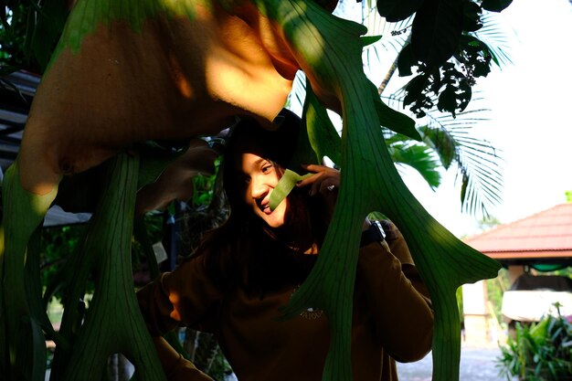 Portrait of young woman standing against plants