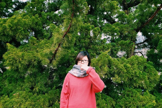 Portrait of young woman standing against plants